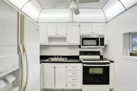 a kitchen with white cabinets and black appliances