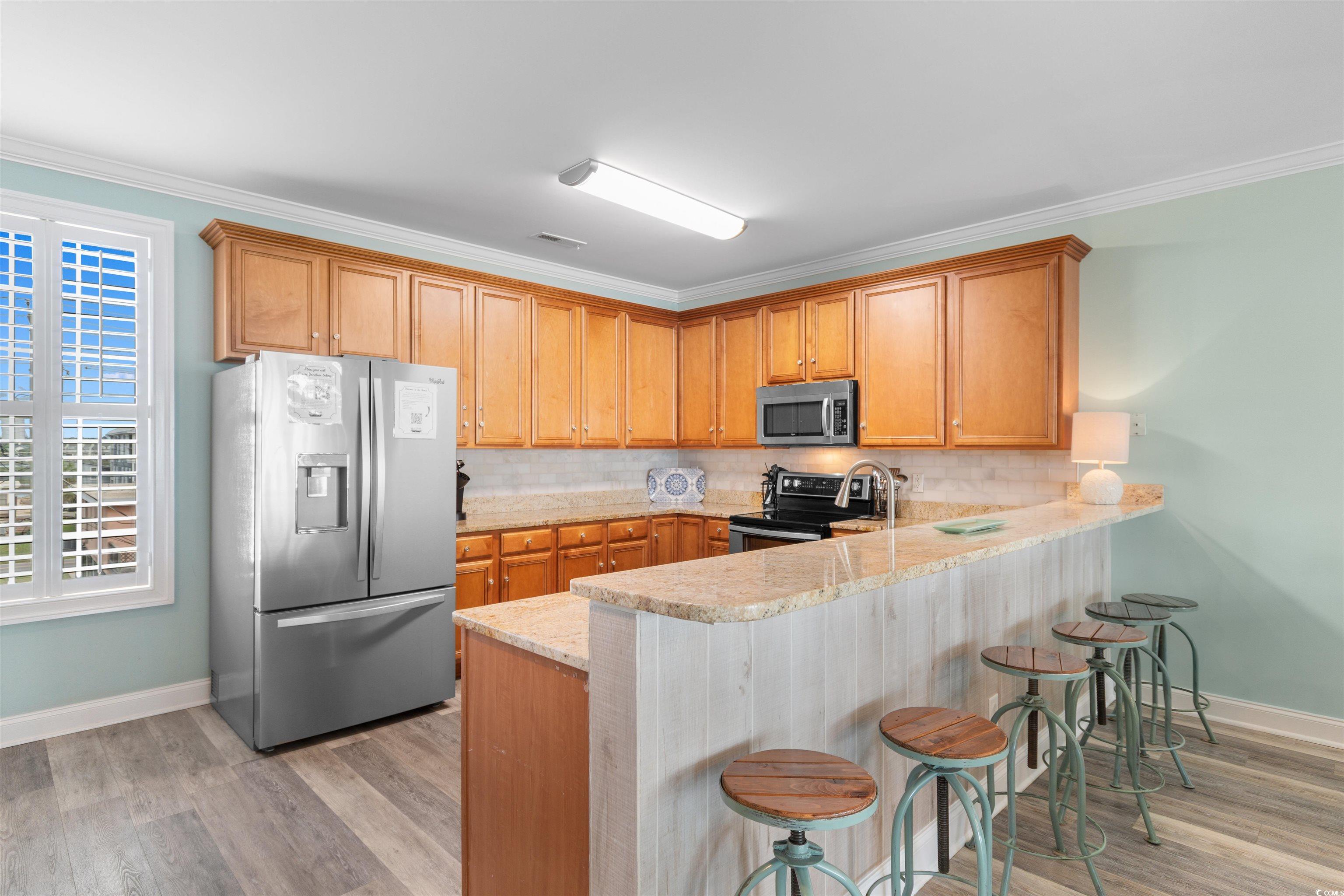 703 South Waccamaw Drive Murrells Inlet, SC 29576 - Photo 12 of 40 Kitchen featuring stainless steel appliances, a peninsula, backsplash