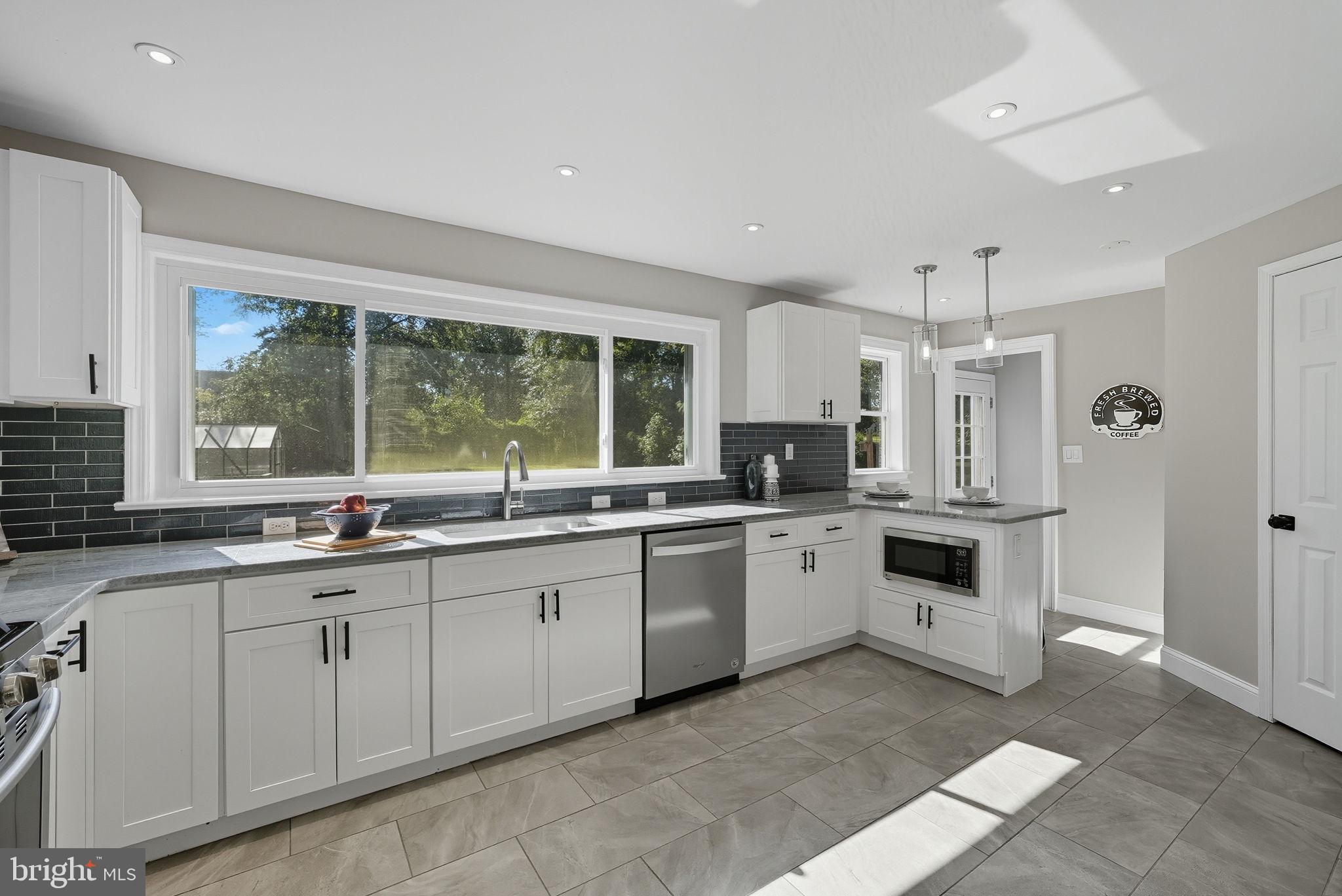 5209 Cedar Road Alexandria, VA 22309 - Photo 11 of 42 a large white kitchen with granite countertop a stove a sink a window and stainless steel appliances