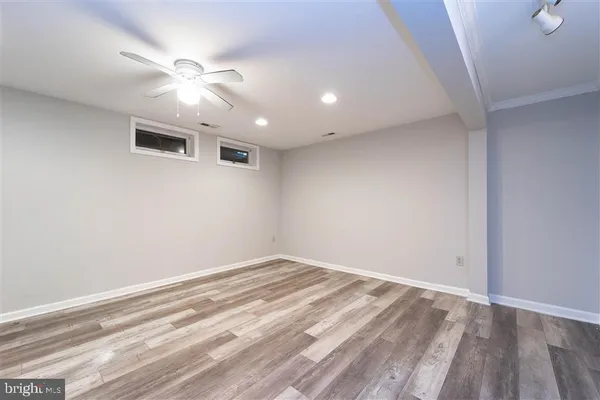 an empty room with wooden floor and fan