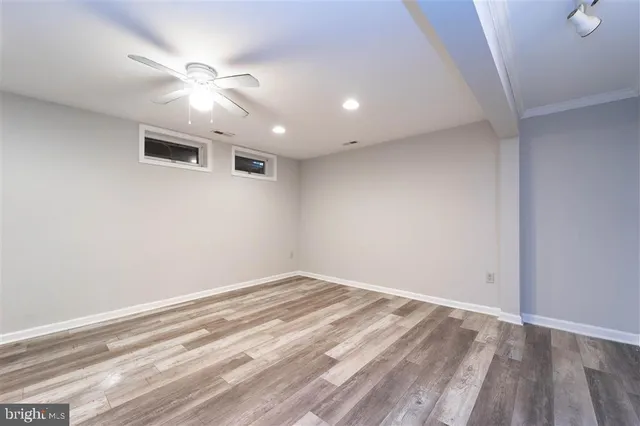 an empty room with wooden floor and fan