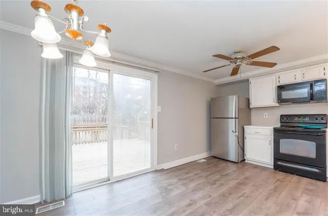 a view of a kitchen with a stove a ceiling fan a refrigerator and a chandelier