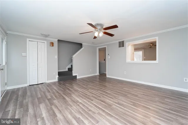 a view of empty room with wooden floor and fan