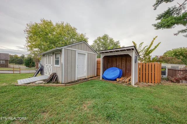 a view of a backyard with a barn and a large tree