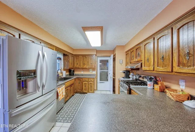 a kitchen with stainless steel appliances granite countertop a refrigerator and a stove top oven