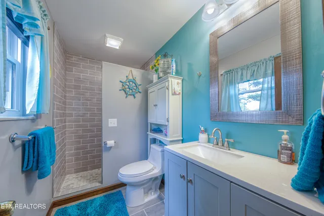 a bathroom with a granite countertop sink a toilet a mirror and shower