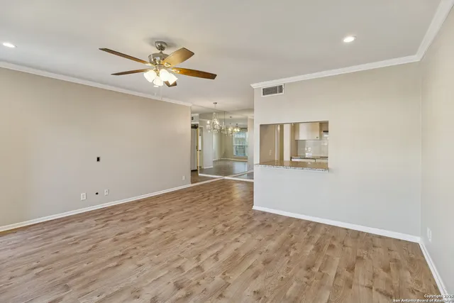 a view of an empty room with window and wooden floor