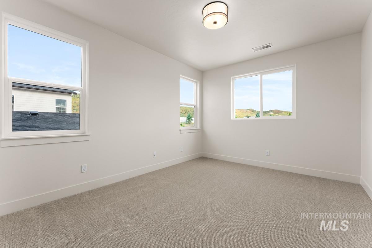 13338 North Spring Creek Way Boise, ID 83714 - Photo 27 of 46 Spacious room featuring light-colored carpeting, white baseboards, and multiple windows with white trim