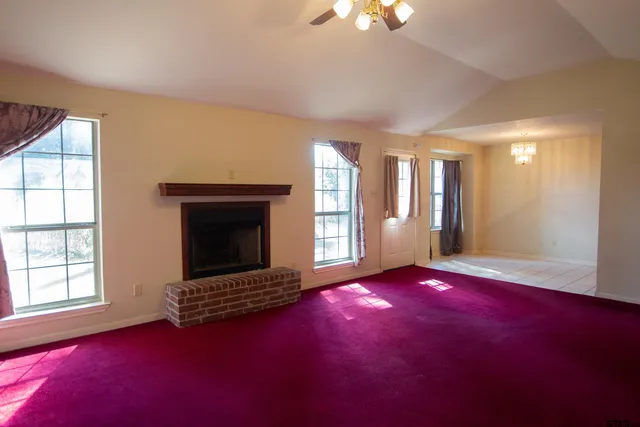 an empty room with windows and fireplace