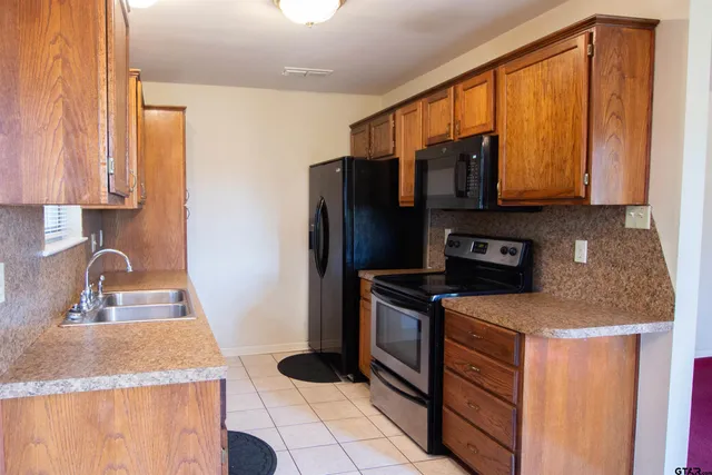 a kitchen with granite countertop a stove a sink and a refrigerator