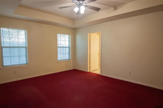 an empty room with windows and chandelier fan