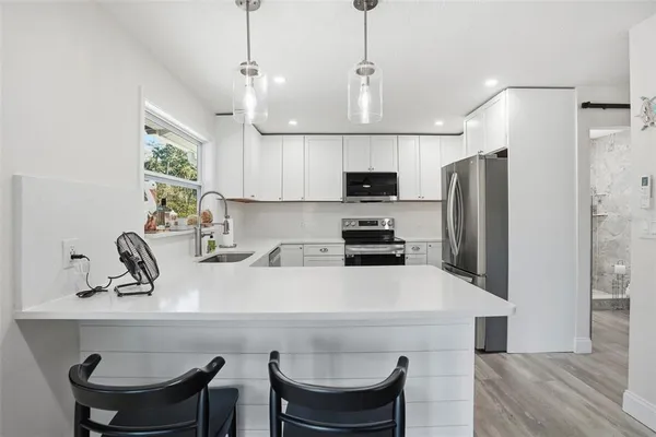 a kitchen with stainless steel appliances a sink a stove a refrigerator and cabinets