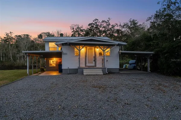 a view of a house with large trees and a small yard