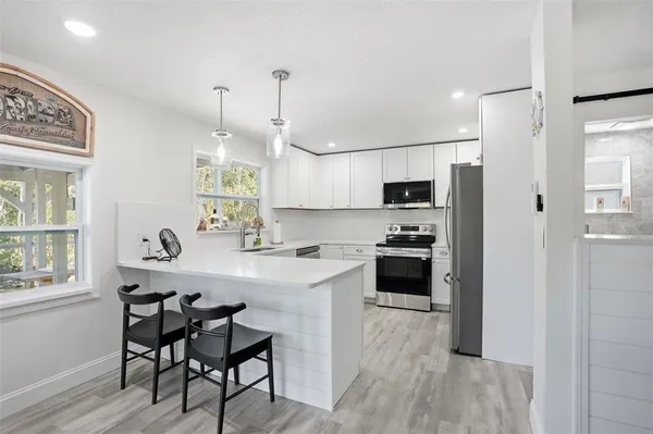 a kitchen with stainless steel appliances granite countertop a stove top oven a sink dishwasher and a refrigerator with wooden floor