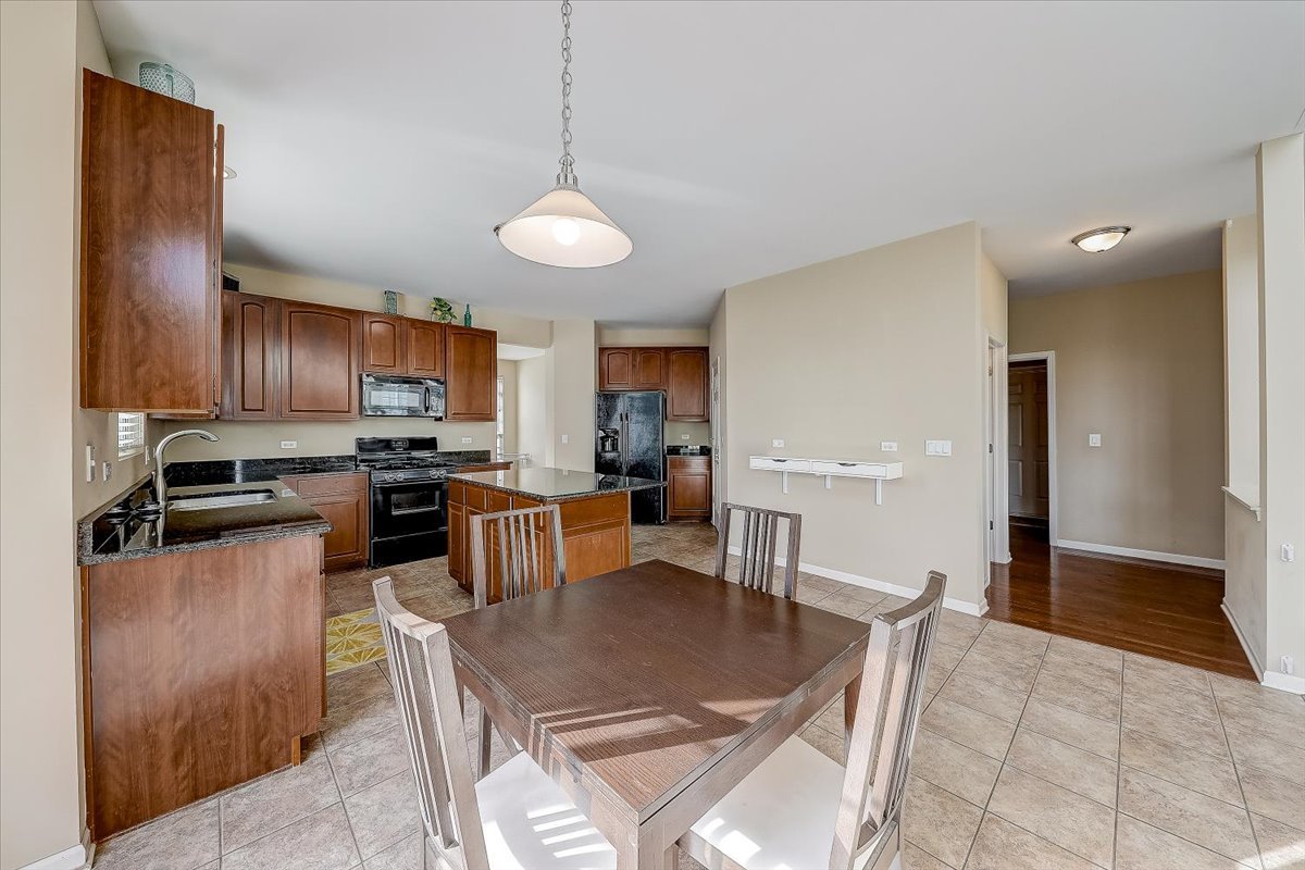406 Aviary Lane Bolingbrook, IL 60490 - Photo 14 of 46 a open kitchen with stainless steel appliances granite countertop a refrigerator a stove a sink a dining table and chairs with wooden floor