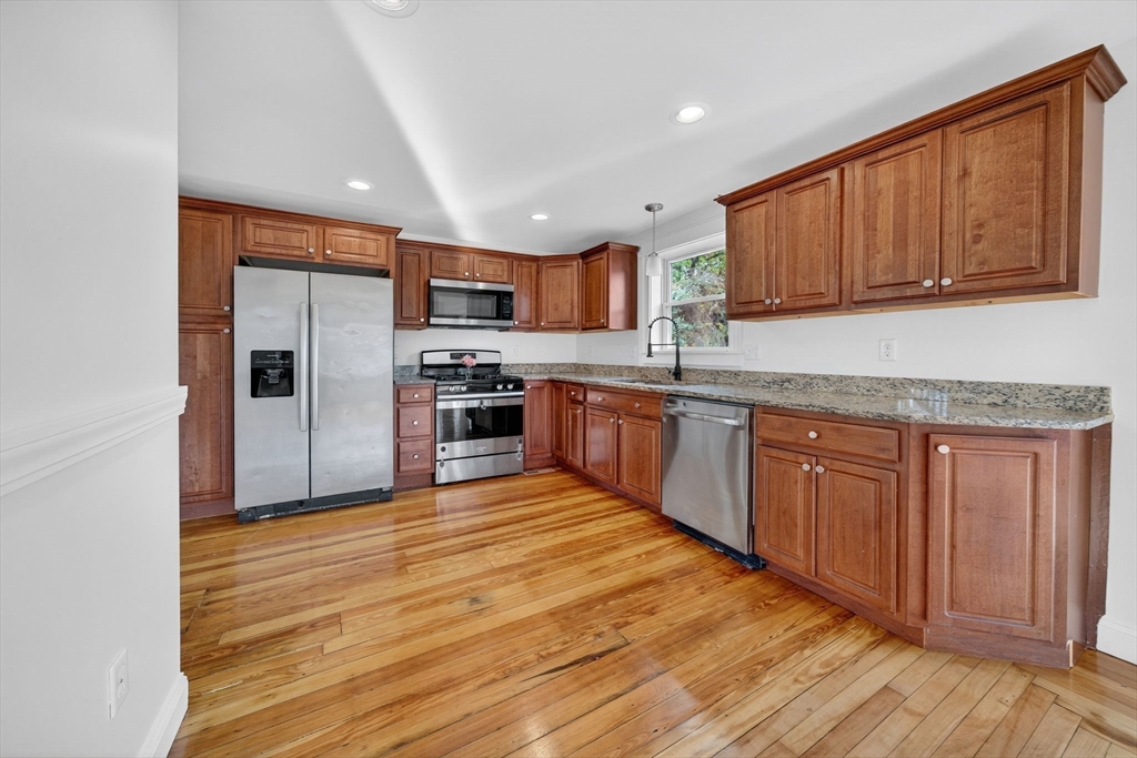 228 Dickinson Street Fall River, MA 02721 - Photo 6 of 40 a kitchen with stainless steel appliances granite countertop wooden cabinets a refrigerator a sink a stove and a wooden floors