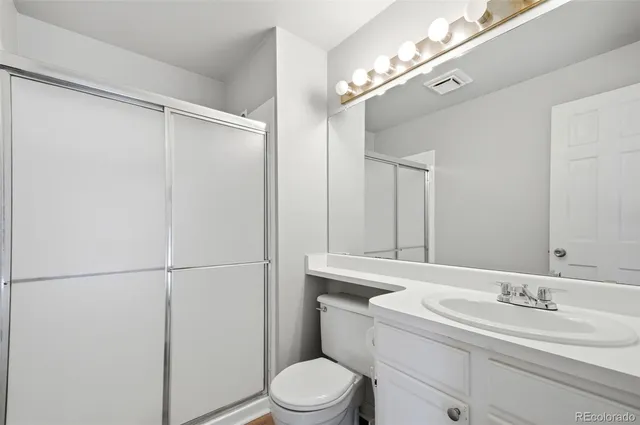 a bathroom with a granite countertop sink mirror vanity and toilet