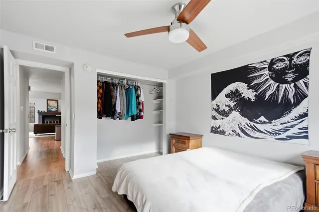 a bedroom with a bed and dresser with wooden floor