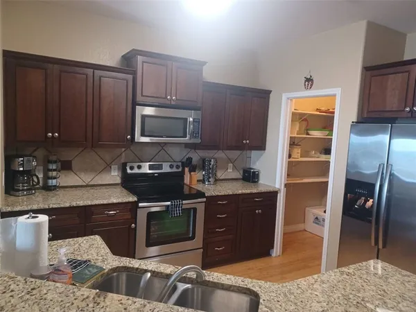 a kitchen with stainless steel appliances granite countertop a stove a sink and a microwave