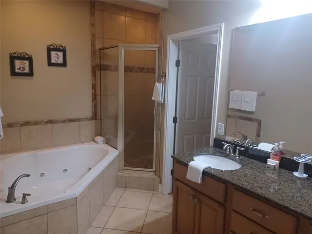 a bathroom with a tub sink double vanity granite and shower