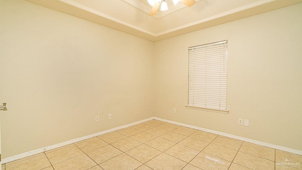 919 Hill Country Road Edinburg, TX 78539 - Photo 12 of 22 Room featuring a tray ceiling, ceiling fan with light fixture, tiled flooring, and a single window with horizontal blinds