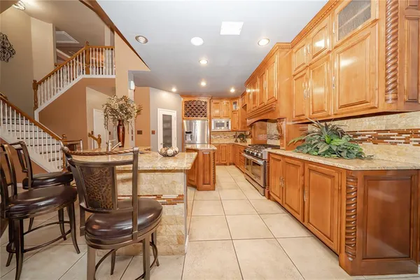 a kitchen with stainless steel appliances kitchen island granite countertop a table chairs and a refrigerator