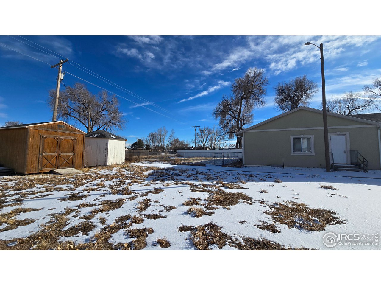 118 Dickson Street Wiggins, CO 80654 - Photo 3 of 34 FROM PARKING LOT SHOWING 2 STORAGE SHEDS