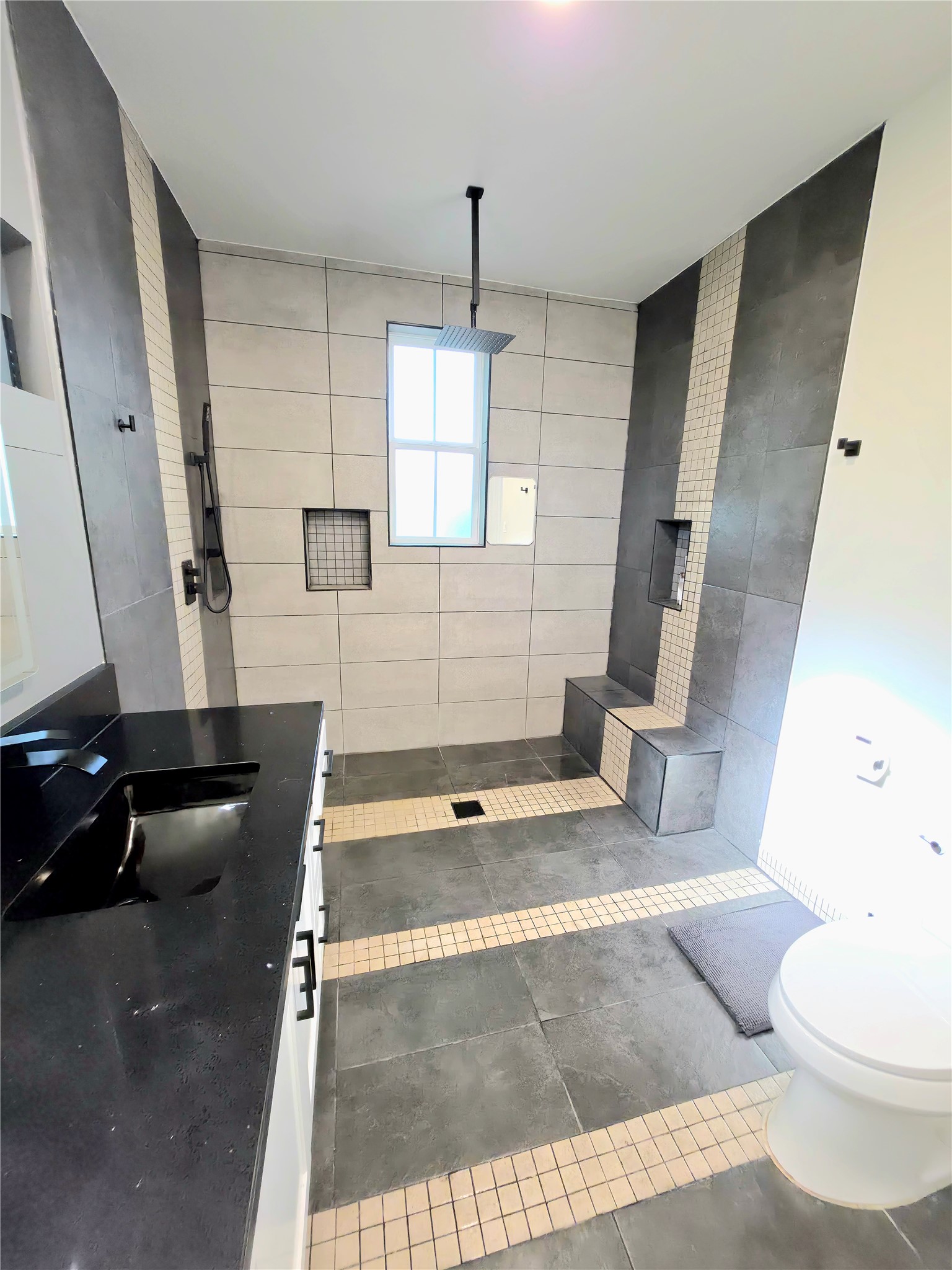 2201 Teri Road Austin, TX 78744 - Photo 16 of 40 Modern tile work and a sleek dark vanity define this contemporary walk-in shower design.
