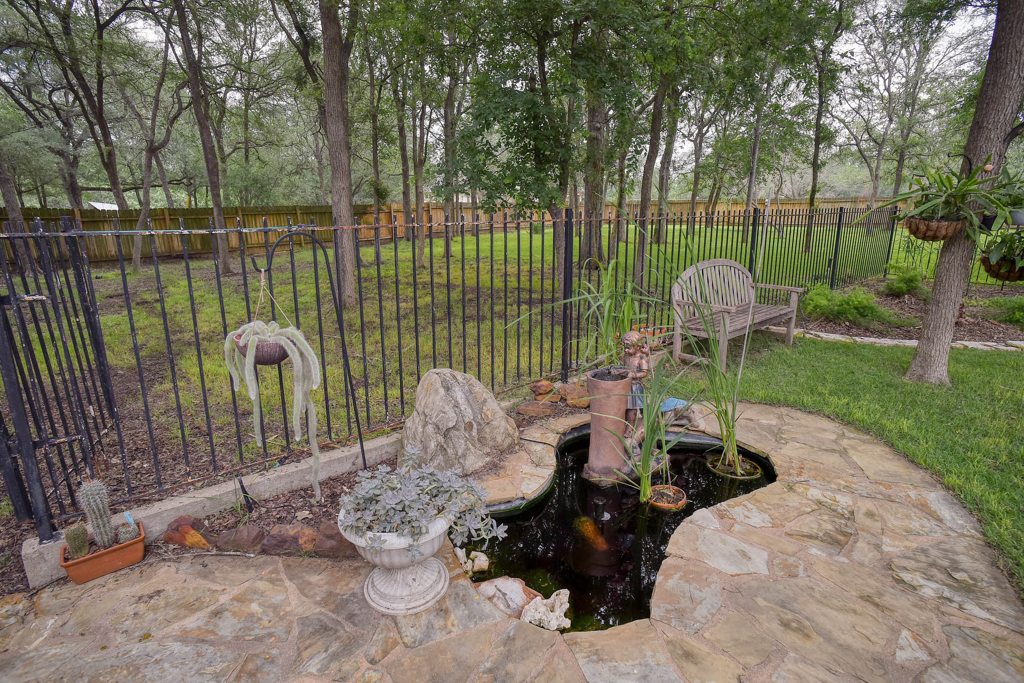 147 Spring Meadow Road Bastrop, TX 78602 - Photo 34 of 40 Flagstone patio with an integrated water feature, surrounded by a black wrought iron fence