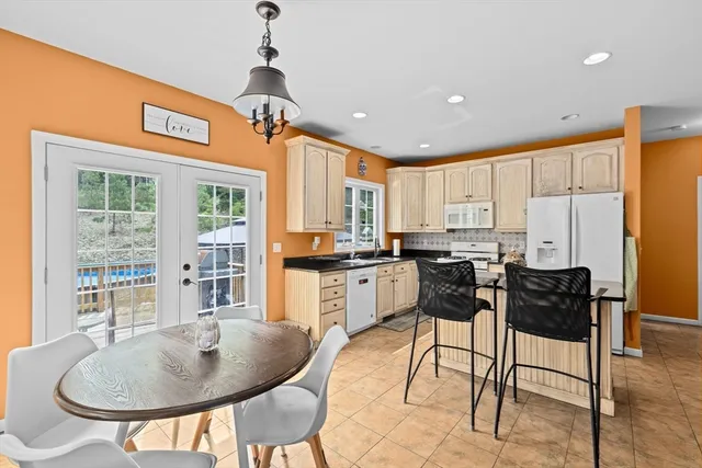 a kitchen with stainless steel appliances kitchen island granite countertop a dining table chairs and a refrigerator