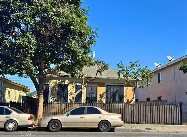 an outdoor view of a house with cars parked