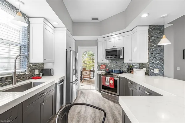 a kitchen with stainless steel appliances granite countertop a sink dishwasher a stove and a refrigerator with wooden floor