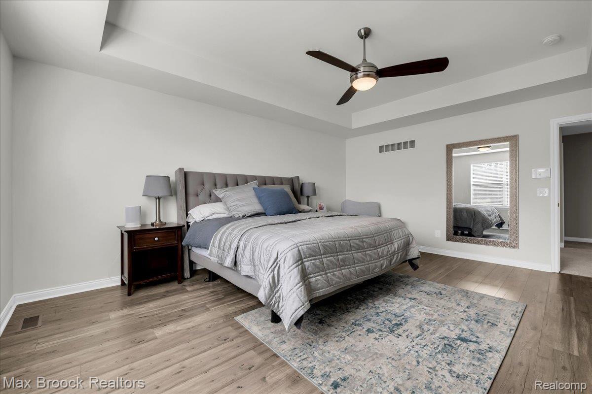 1126 Queensboro Drive Rochester, MI 48307 - Photo 39 of 66 Spacious bedroom featuring a tray ceiling, wood-finish flooring, and a contemporary ceiling fan