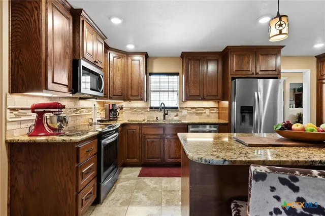 a kitchen with kitchen island a stove a refrigerator and a dining table with wooden floor