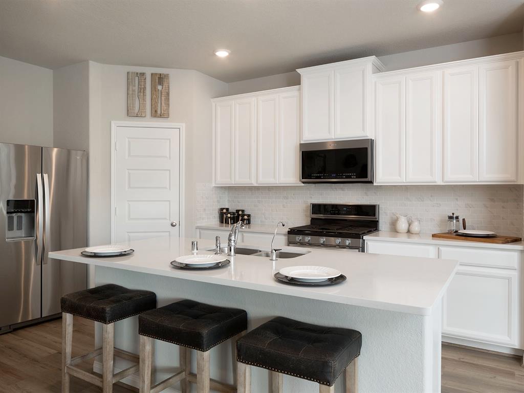 a kitchen with stainless steel appliances a stove a sink cabinets and a refrigerator