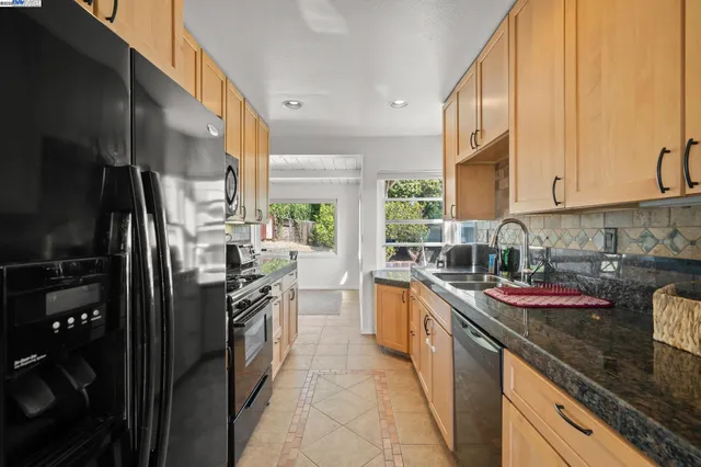 a kitchen with granite countertop stainless steel appliances a sink stove top oven and cabinets