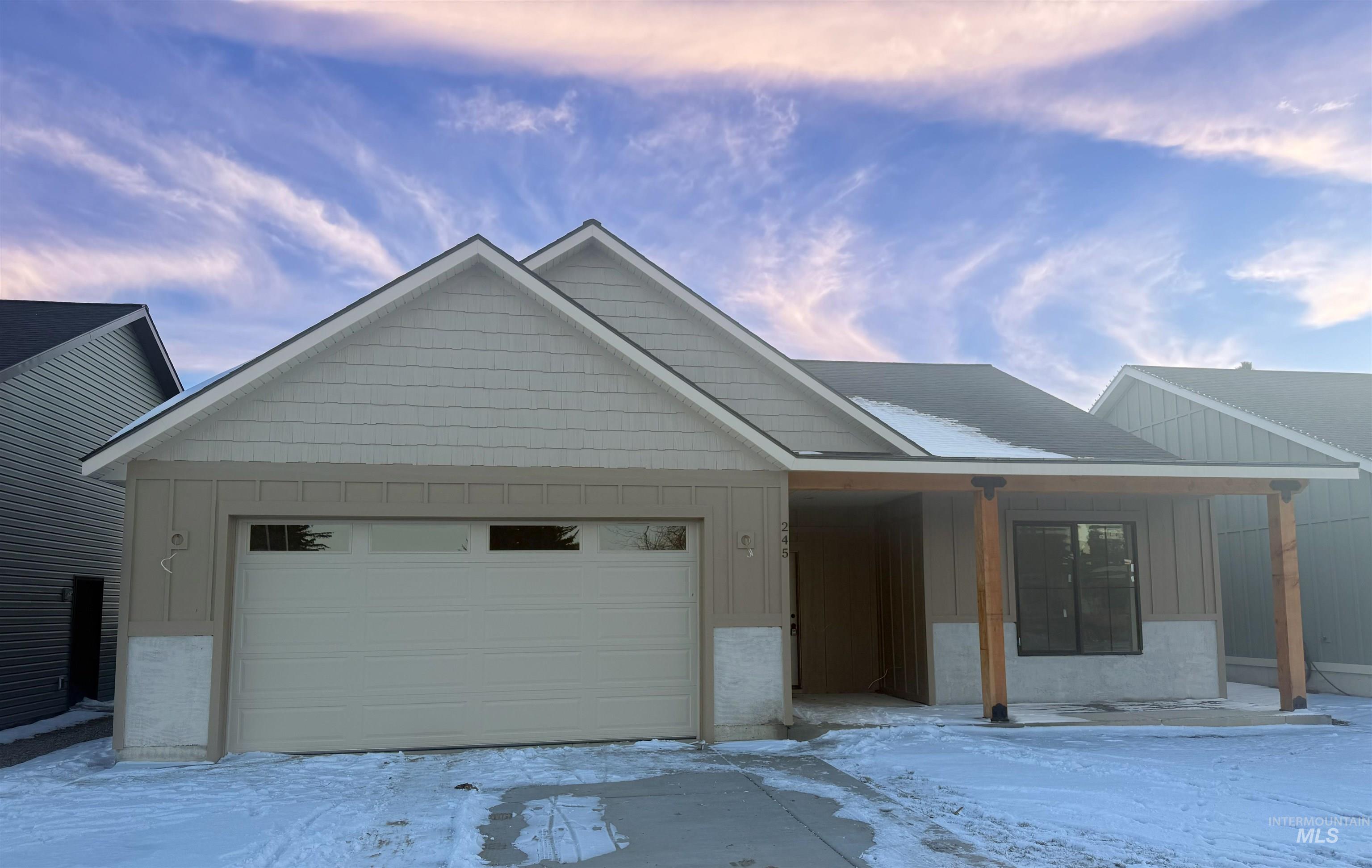 View of front of house with board and batten siding, a garage, and covered porch