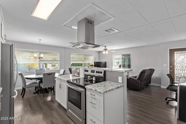 a kitchen with stainless steel appliances granite countertop a stove and chairs