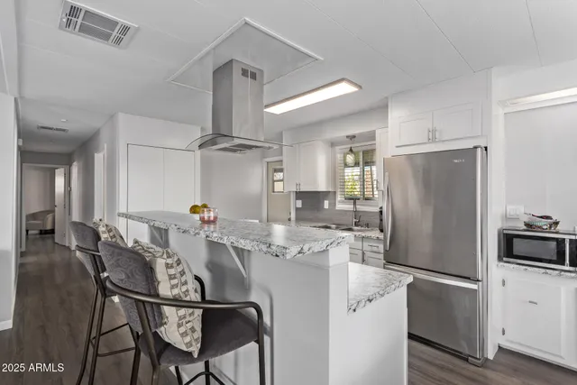 a kitchen with stainless steel appliances a refrigerator a stove a dining table and chairs with wooden floor