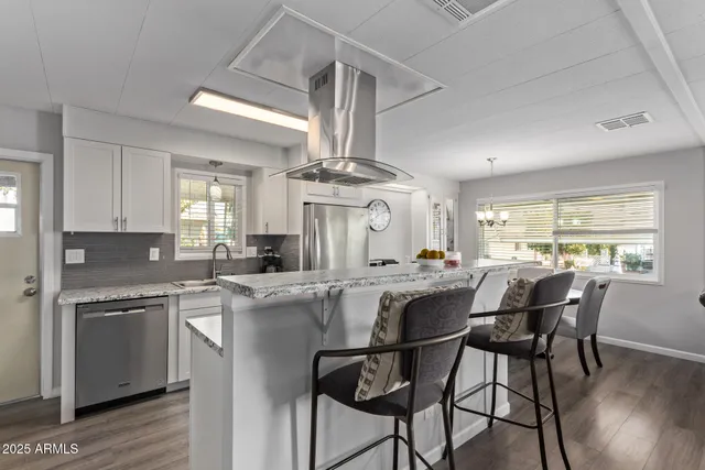 a kitchen with stainless steel appliances a dining table chairs and wooden floor