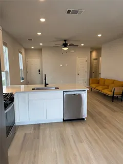 a large kitchen with stainless steel appliances a large counter top a stove and a wooden floors