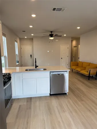 a large kitchen with stainless steel appliances a large counter top a stove and a wooden floors