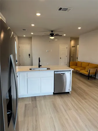 a large kitchen with stainless steel appliances a large counter top a sink a refrigerator and a window