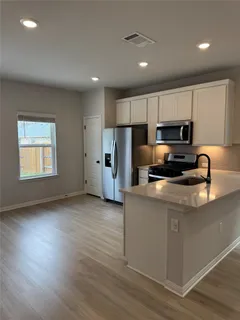 a kitchen with granite countertop a refrigerator and a stove top oven