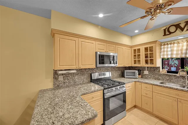 a kitchen with stainless steel appliances granite countertop a stove a sink and a microwave