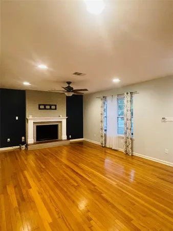 a view of empty room with a fireplace and wooden floor