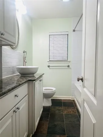 a bathroom with a granite countertop sink a toilet and bathtub