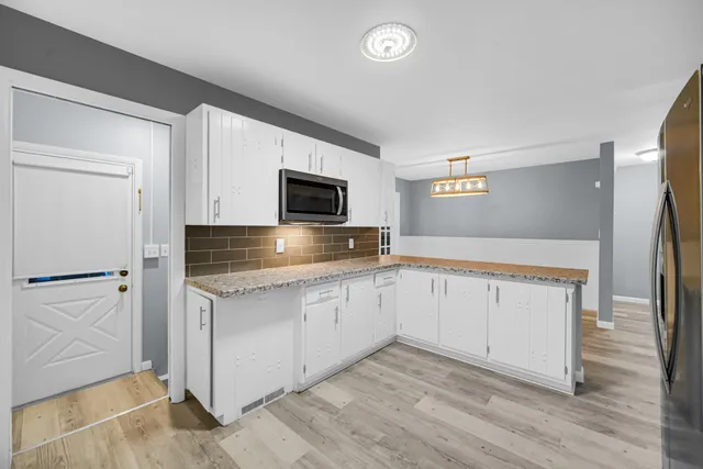 a kitchen with granite countertop white cabinets and stainless steel appliances