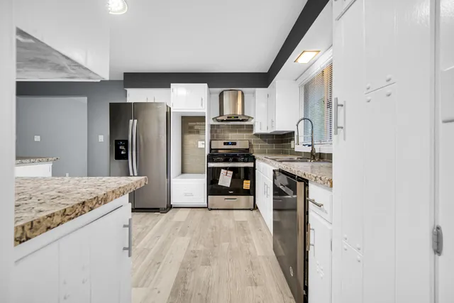 a kitchen with stainless steel appliances granite countertop a refrigerator and a stove