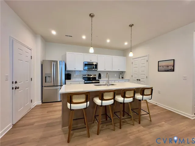 a kitchen with a sink chandelier and wooden floor